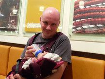 Sunny wird von Papa in der Trage gefüttert